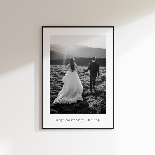 happy anniversary darling print with black and white monochrome personalised image of a married couple in a field in wedding dress and suit. Print is framed in a black frame