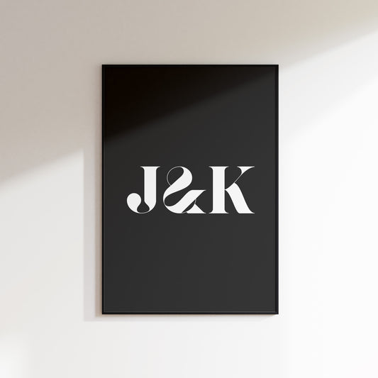 An initials print for the home, ideal for hallways, living rooms and bedrooms. This is a slate coloured print with a white uppercase ‘J & K’ in a high contrast serif typeface. Print is in a black frame on a white wall background.